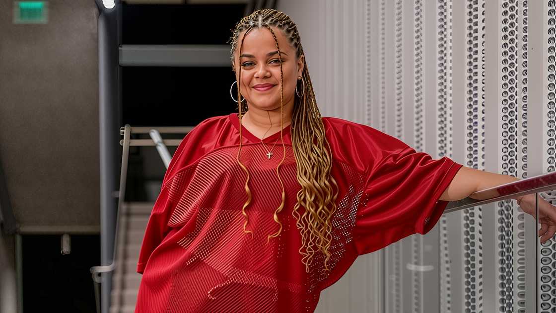 Piper Gooding poses standing in a red shirt.