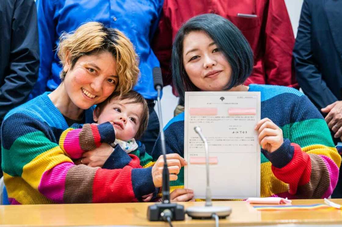 Mamiko Moda (L) and her partner Satoko Nagamura, along with their son, hold a same-sex partnership certificate at a Tuesday press conference