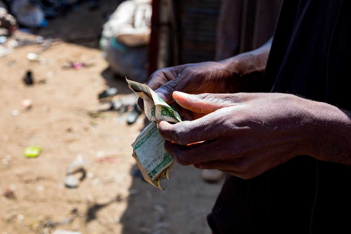 A person holding and counting worn paper money outdoors. A person holding and counting worn paper money outdoors.