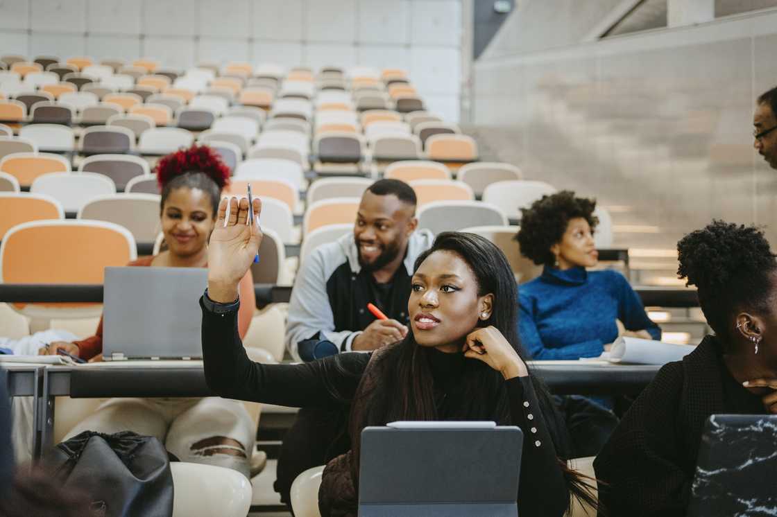 Young female student raising hand during lecture in class