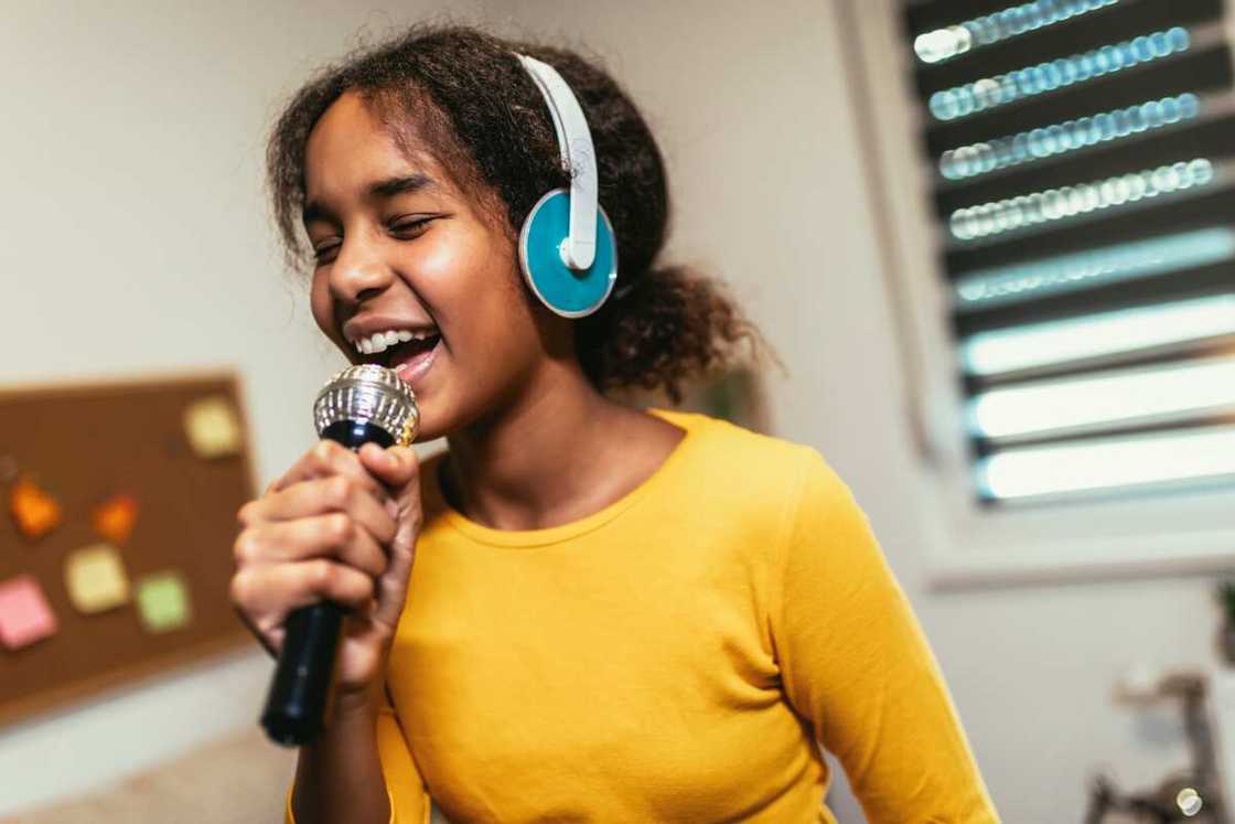 A girl holding microphon singing karaoke at home.