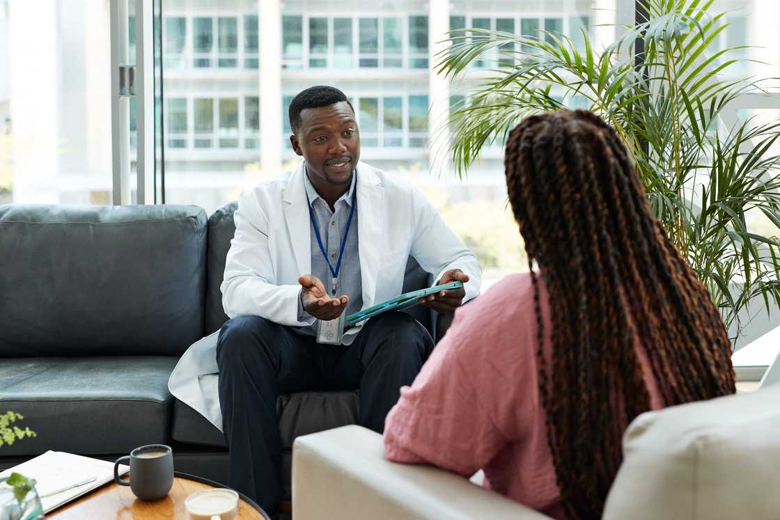 A healthcare professional holding a tablet PC and advising a patient A healthcare professional holding a tablet PC and advising a patient