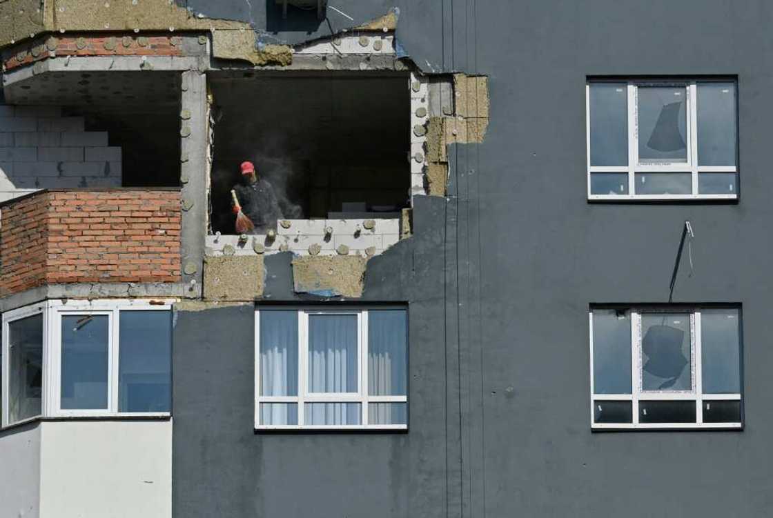 A construction worker sweeps dust from a damaged flat during repair work at an apartment block destroyed by shelling in Irpin