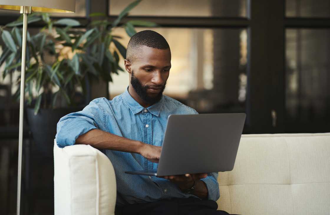 A black man with a laptop in the living room