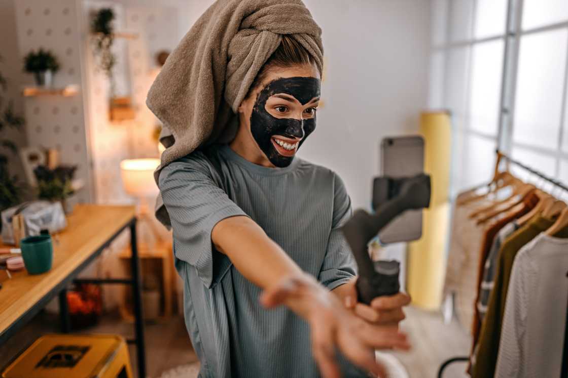 A women with black charcoal facial mask on a video call. A women with black charcoal facial mask on a video call.