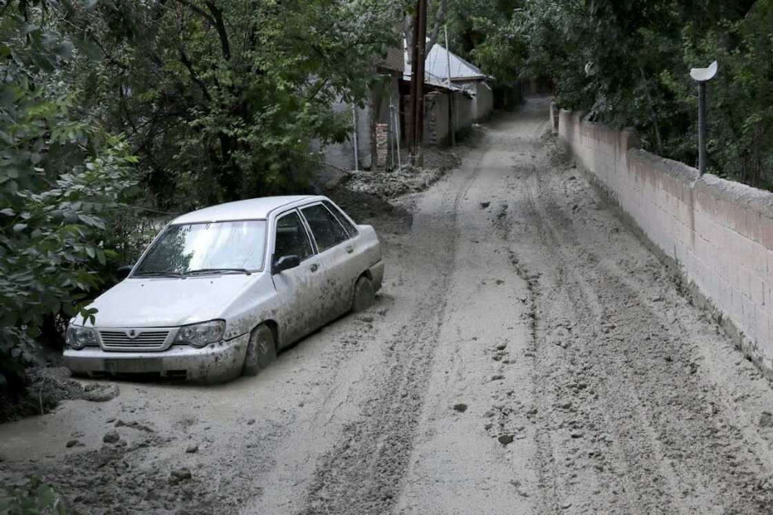 A car partially buried in mud on a road in the Firouzkouh area A car partially buried in mud on a road in the Firouzkouh area