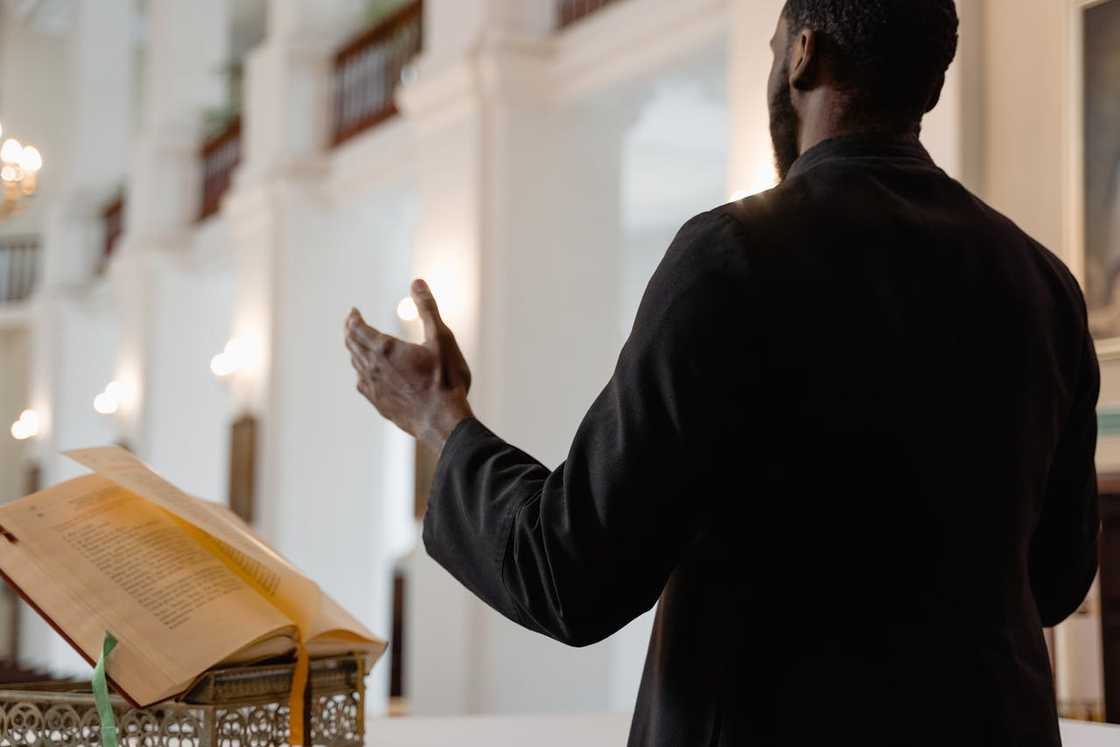 A priest preaching from a lectern inside a large church hall.