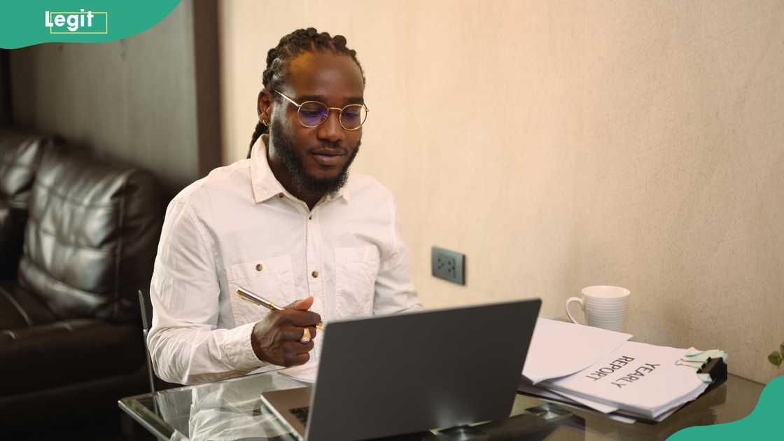A young man in glasses working with a laptop and documents at home A young man in glasses working with a laptop and documents at home