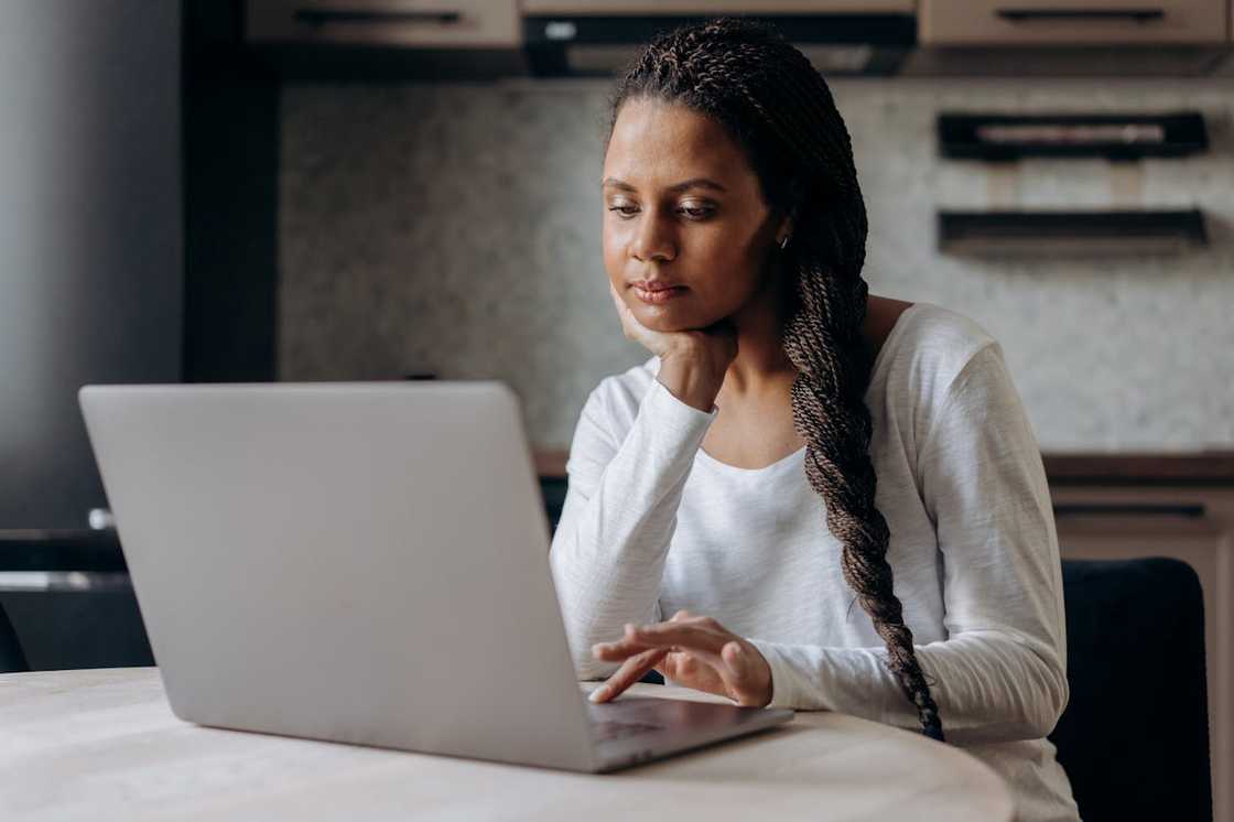 A woman working on a laptop at a kitchen table.