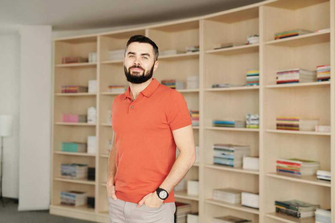 A man wearing an orange polo shirt in a library