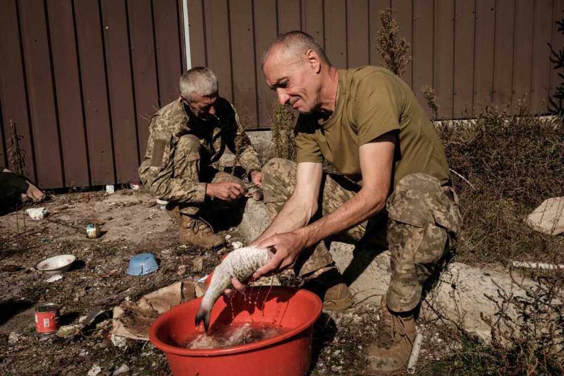 Ukrainian soldiers clean fish they have caught for cooking, in the recently recaptured resort village of Shchurove Ukrainian soldiers clean fish they have caught for cooking, in the recently recaptured resort village of Shchurove