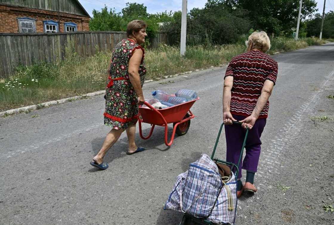 Women transport water bottles in a wheelbarrow and trolley Women transport water bottles in a wheelbarrow and trolley