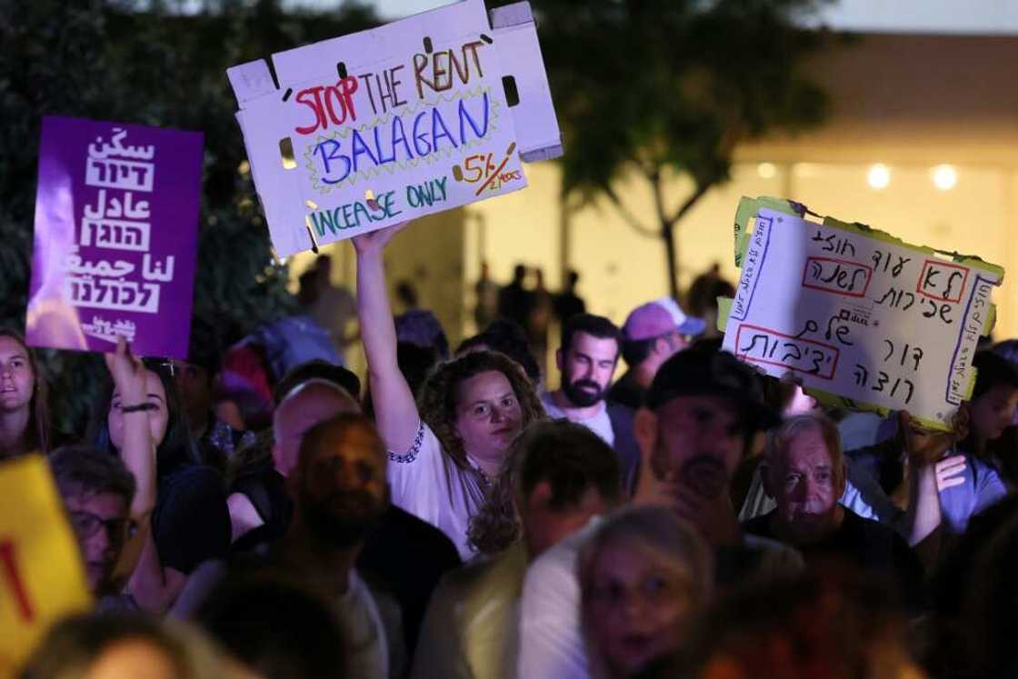 Israelis wave placards as they gather in the coastal city of Tel Aviv to demonstrate against the increase in prices in the real estate market on July 2, 2022