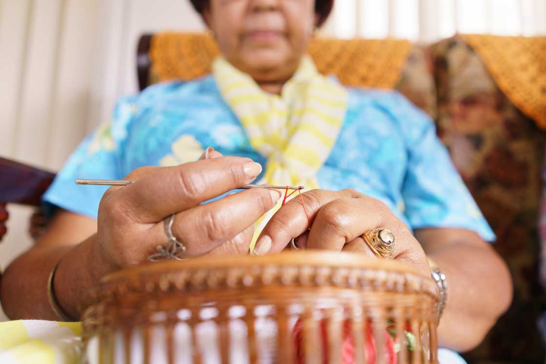An elderly woman knitting in a cozy living room.