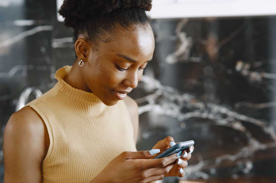 A close-up of a woman in a brown sleeveless top using a smartphone A close-up of a woman in a brown sleeveless top using a smartphone