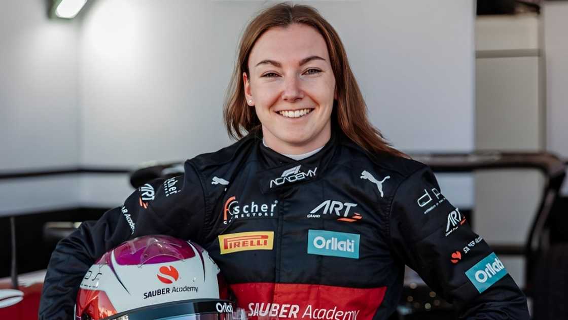 Léna Bühler poses in a racing uniform and helmet. Léna Bühler poses in a racing uniform and helmet.