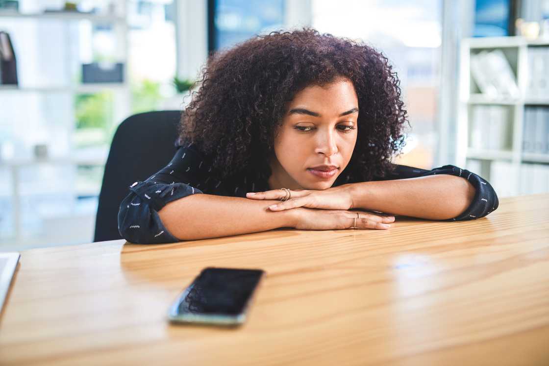 A young woman sitting staring at at her cellphone