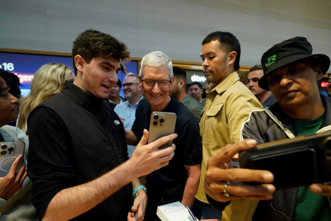 Apple CEO Tim Cook (C) joins customers during Apple's iPhone 16 launch in New York on September 20, 2024