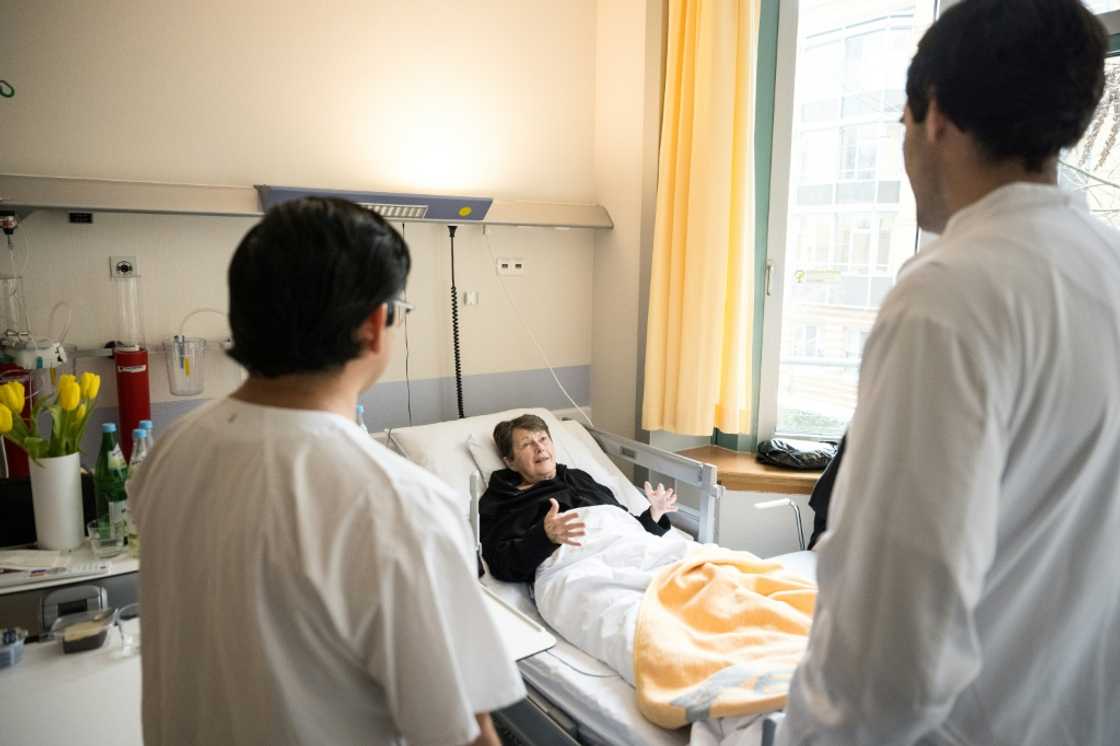 Mexican doctor and neurologist in training Mario de la Piedra Walter (R) and nursing professional Lorenzo Santiago Fernandez Yam from Mexico chat with patient Sibylle Hasenbein at a hospital Berlin on February 13, 2025 in Berlin. National elections on February 23, 2025 are expected to deliver victory for the conservative CDU/CSU bloc and a strong second-place showing for the far-right Alternative for Germany (AfD). Both parties have promised a crackdown on immigration, with the AfD campaigning in parts of the country with fake plane tickets to send illegal migrants on a one-way journey home. Hospital managers are "worried" that tensions over immigration will make it harder for Germany to recruit enough skilled workers from abroad to fill a growing labour shortage.