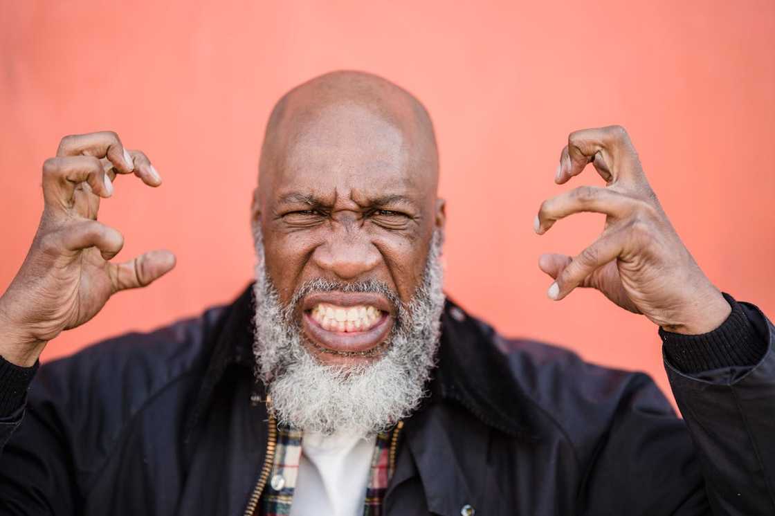 A man grimaces with his hands raised in an aggressive pose.