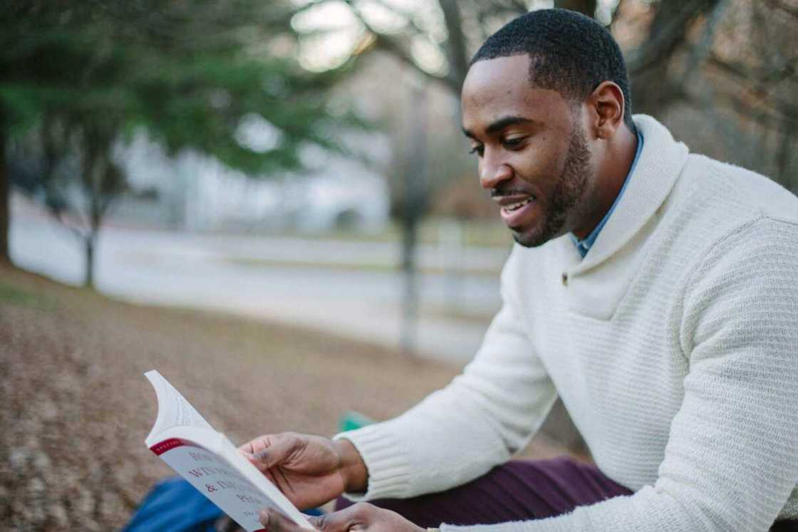 A man in a white sweater reading a book A man in a white sweater reading a book