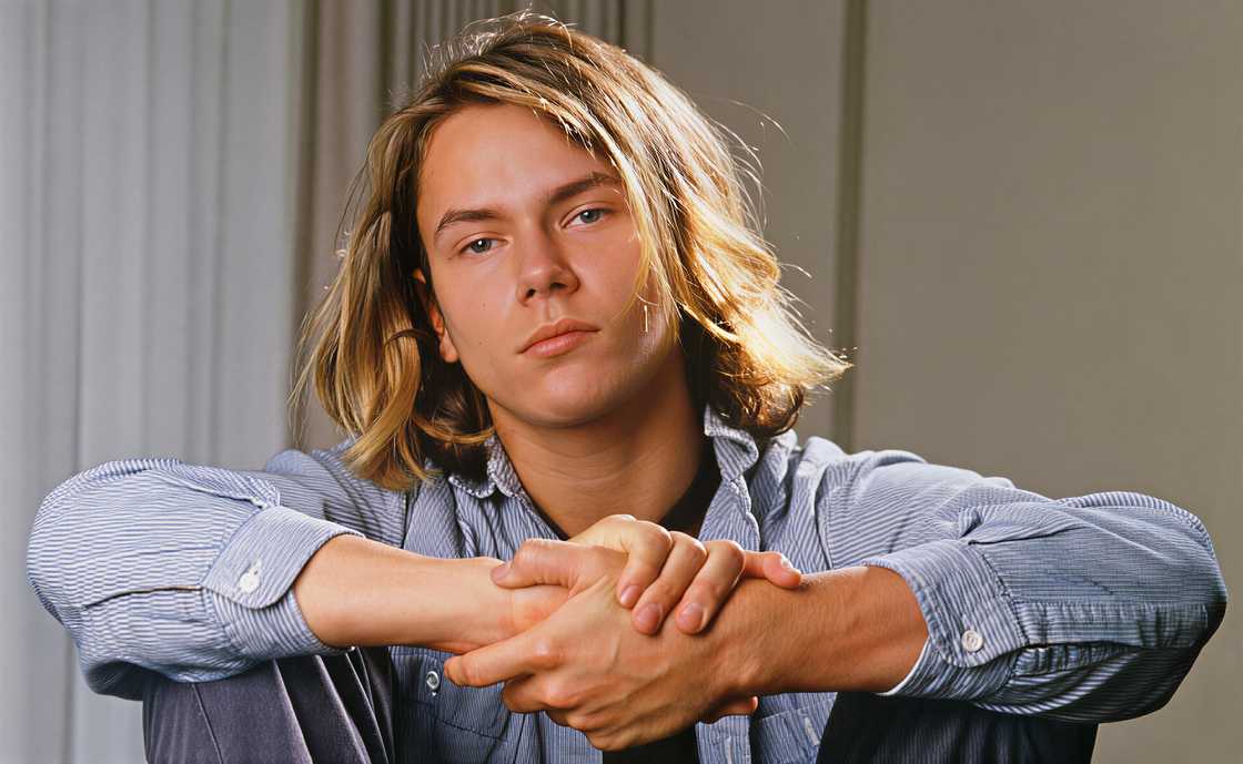 River Phoenix poses sitting while holding his hands