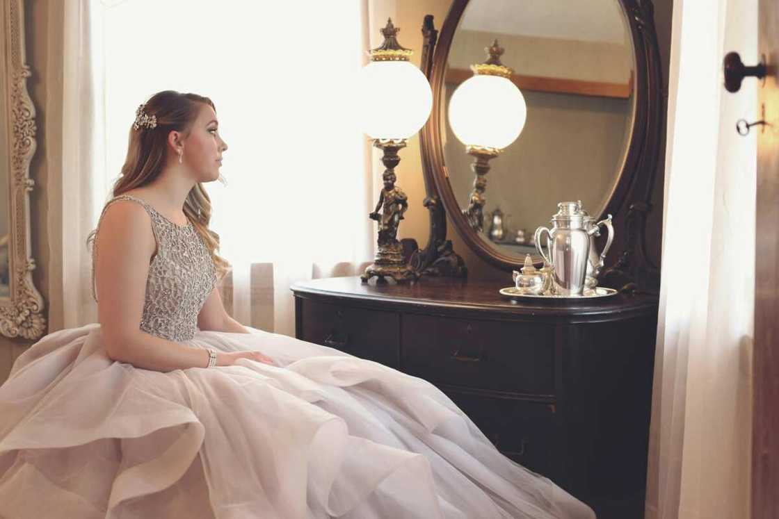 A woman wearing a gown looking at mirror