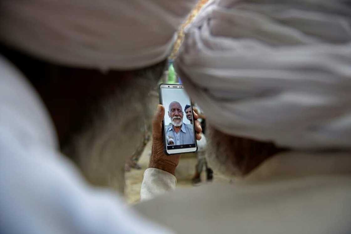 Sikh labourer Sika Khan (R) talks to his elder brother Sadiq Khan in Pakistan via a mobile video call