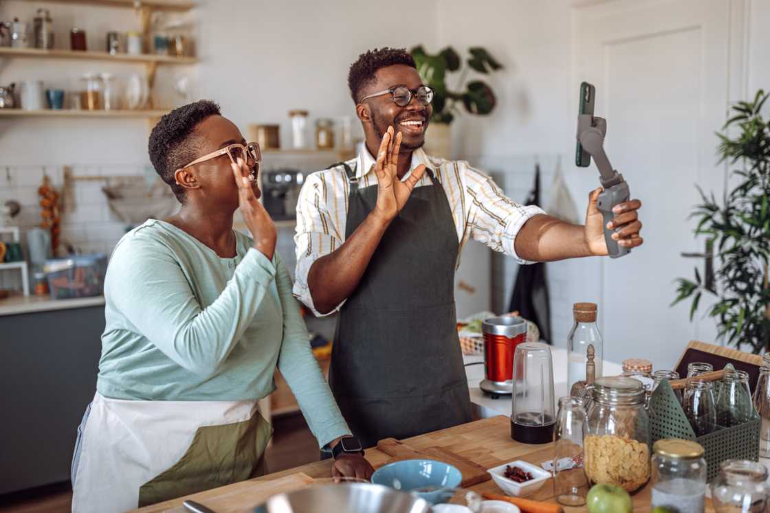 A couple laughs while filming a cooking video in their Lagos kitchen.