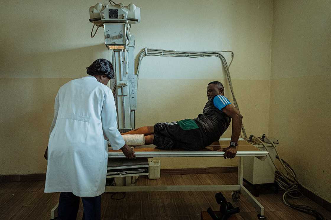 An A1-level radiology technician positions a patient on the X-ray table An A1-level radiology technician positions a patient on the X-ray table