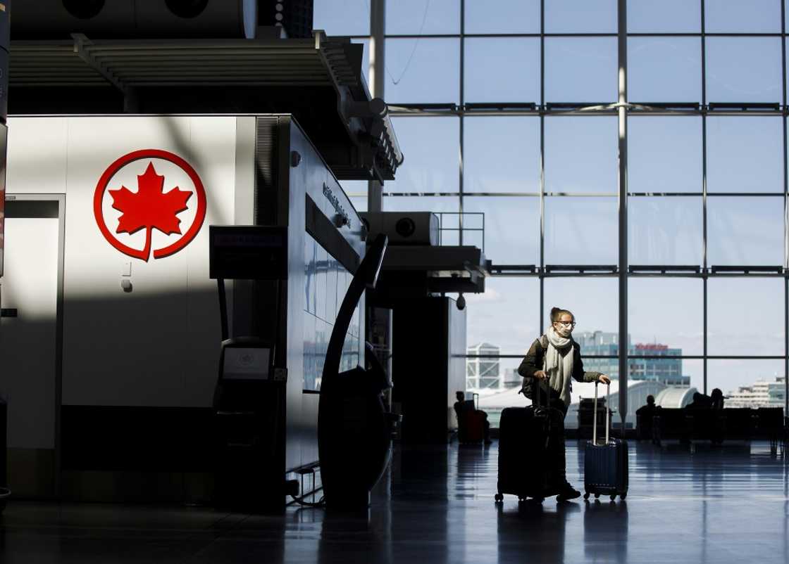 A passenger wheels her luggage near an Air Canada logo at Toronto Pearson International Airport in April 2020