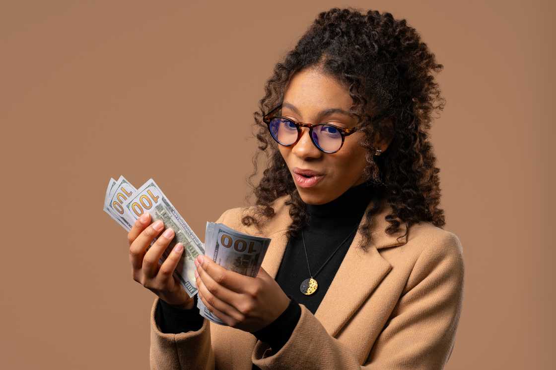 An excited curly teenage girl counting cash An excited curly teenage girl counting cash