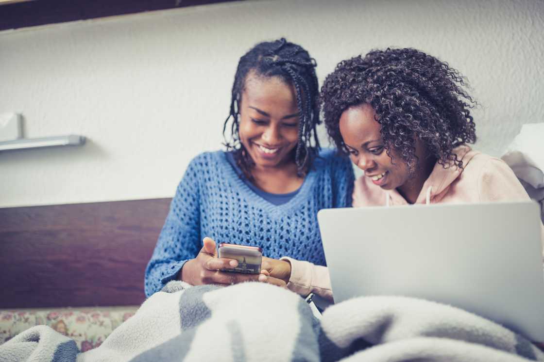 Two young women studying together in a cosy university dorm room.