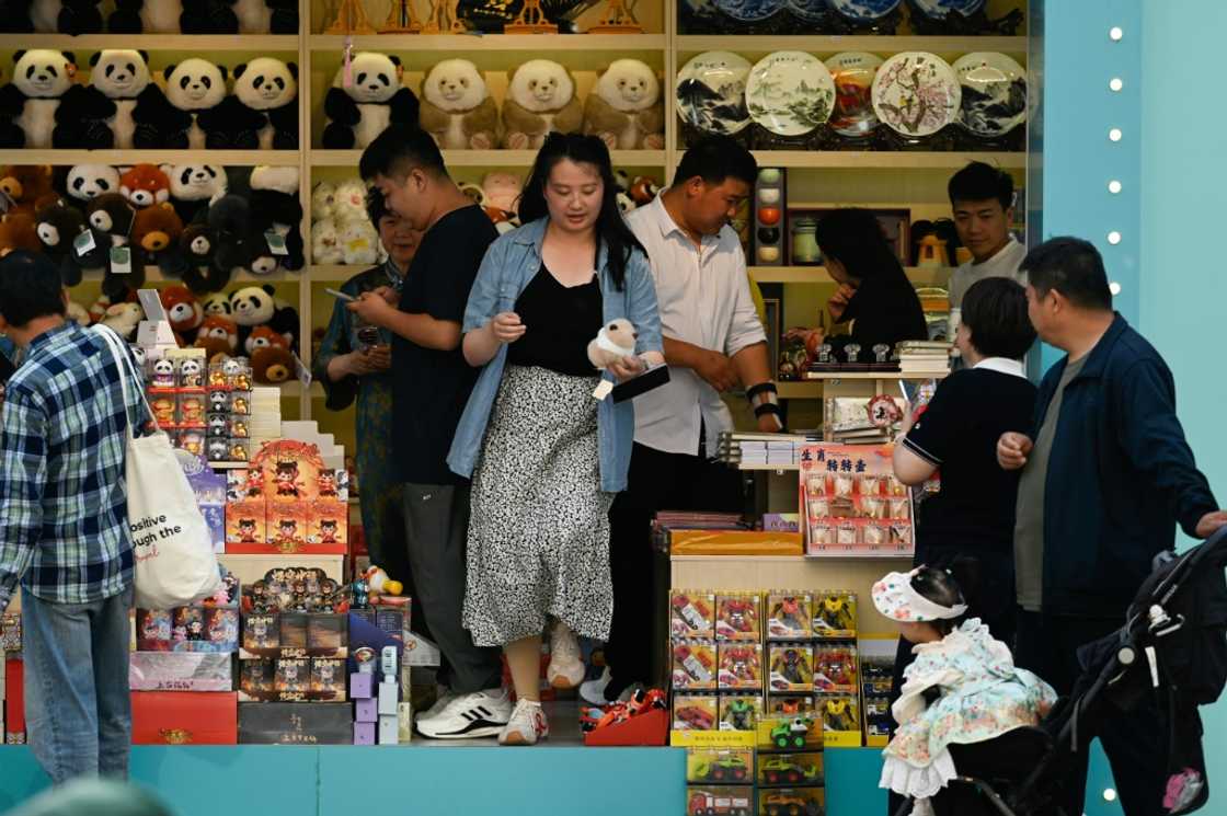 People visit a shop along a busy street in Beijing People visit a shop along a busy street in Beijing