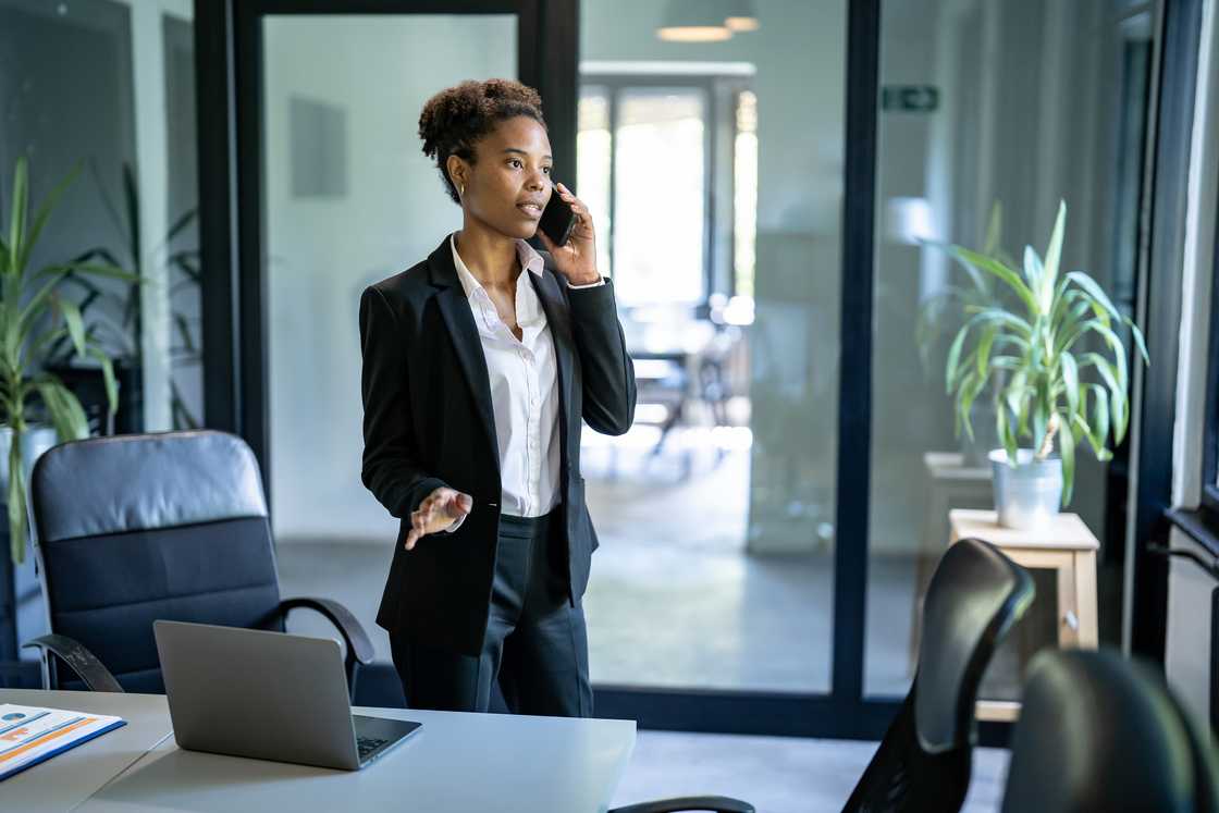 A lady standing at her desk and talking on the phone A lady standing at her desk and talking on the phone