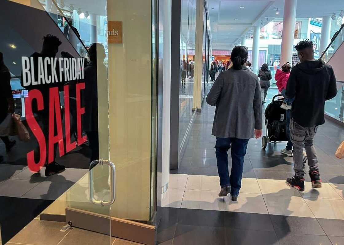 A family walks past a store advertising a Black Friday sale near Pentagon City Mall in Arlington, Virginia