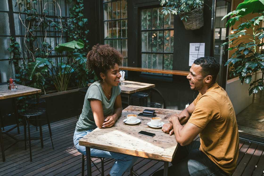 A young couple talking while sitting at a table in a cafe A young couple talking while sitting at a table in a cafe