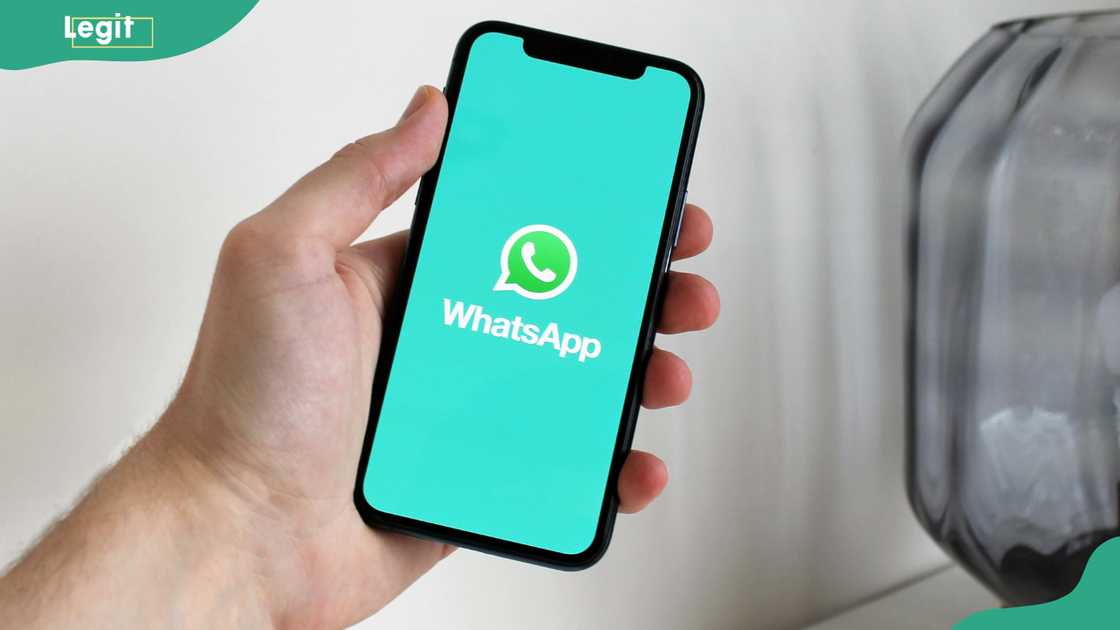 A person holding a cellphone with a WhatsApp logo on the screen