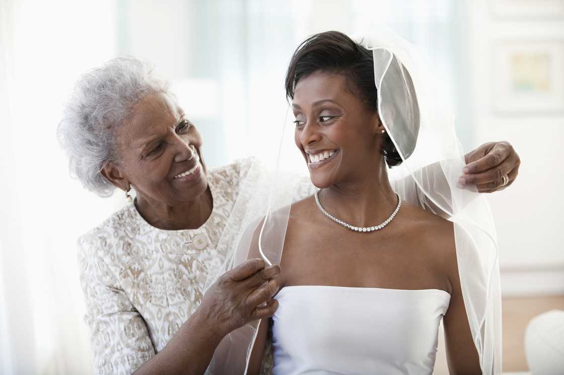 An older woman helping a bride with her veil. An older woman helping a bride with her veil.