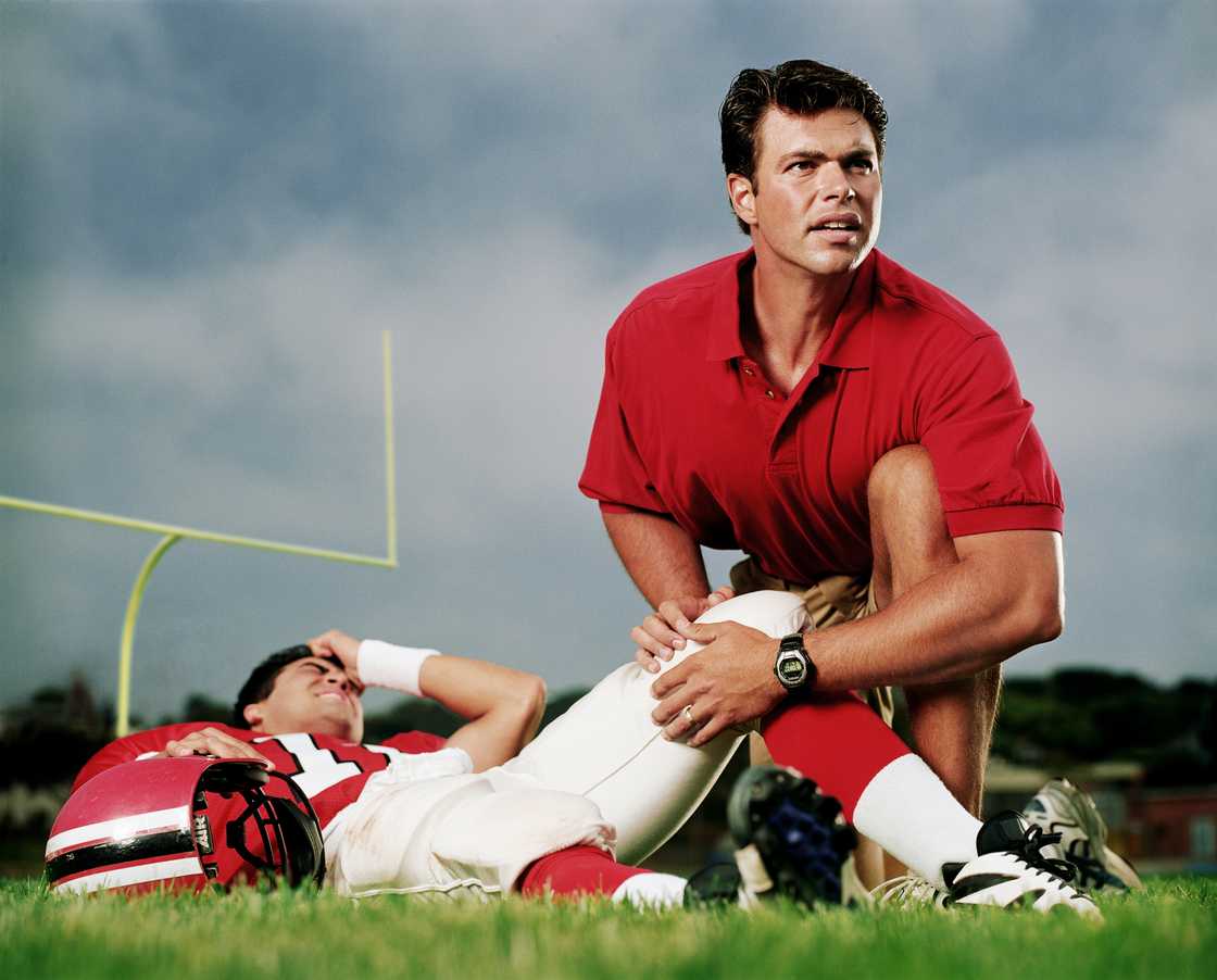 A football team doctor with an injured player on the field A football team doctor with an injured player on the field