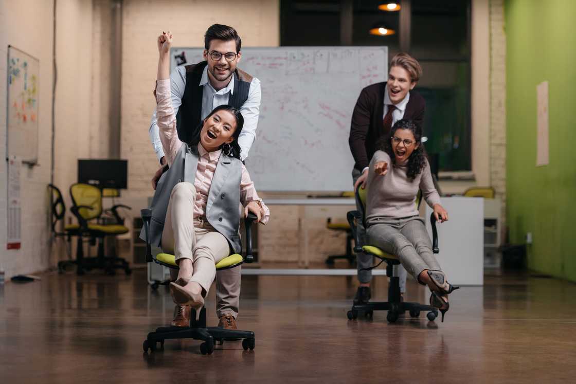 Two men pushing the ladies on swivel chairs in the office. Two men pushing the ladies on swivel chairs in the office.