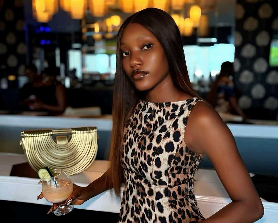 Oyin from BBNaija holds a drink in a restaurant