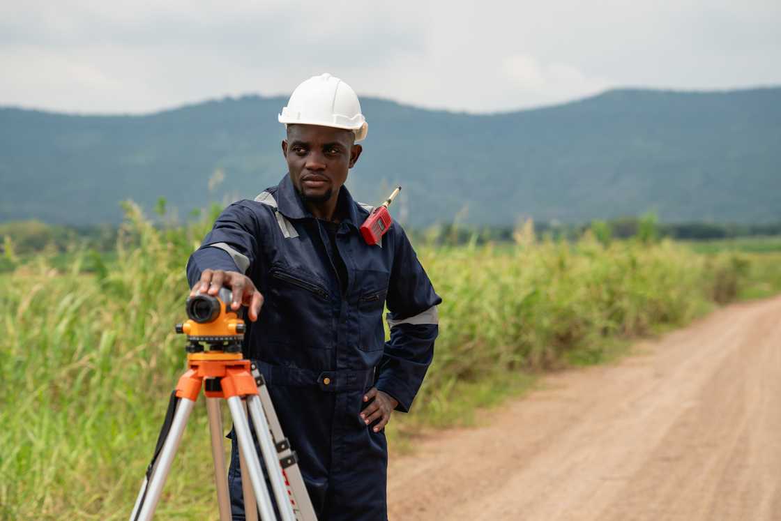 An road construction worker surveys a road under construction An road construction worker surveys a road under construction