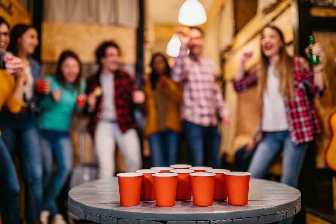 Young people playing Beer Pong in hostel Young people playing Beer Pong in hostel