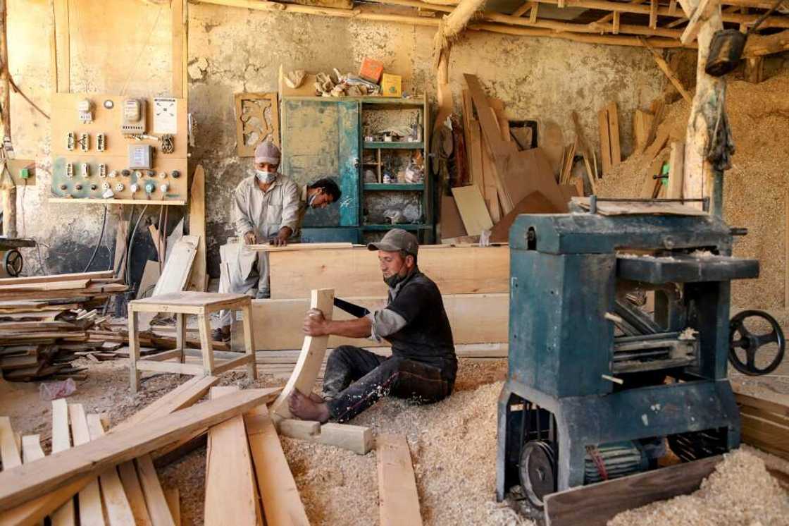 Without a reliable energy supply, carpenters use a fuel generator to keep business in operation, puffing out emissions that contribute to global warming