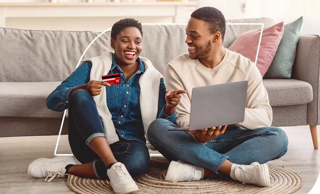 A son holding a debit carer and a father using a laptop