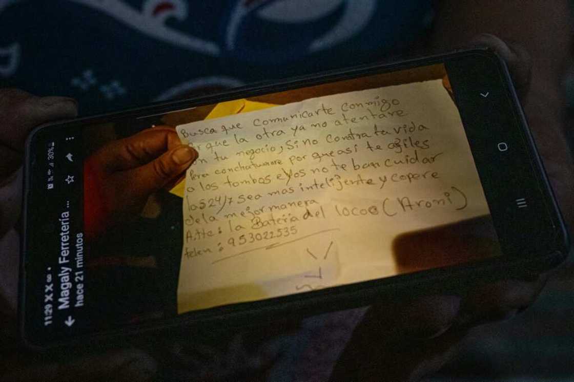 A merchant shows a photograph of a threatening note she received from a gang trying to extort her A merchant shows a photograph of a threatening note she received from a gang trying to extort her