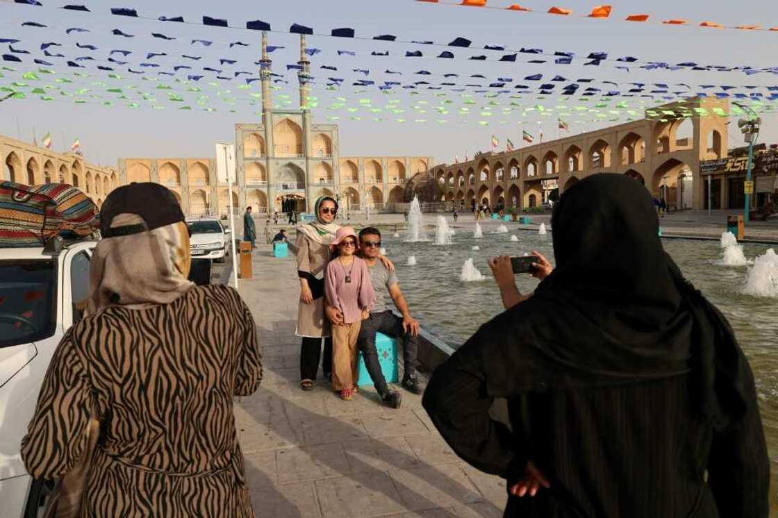 People pose for a photo before the medieval Timurid-era mosque of Amir Chakhmaq (also known as Dahouk mosque), completed in 1438, in Yazd in central Iran on July 4, 2023