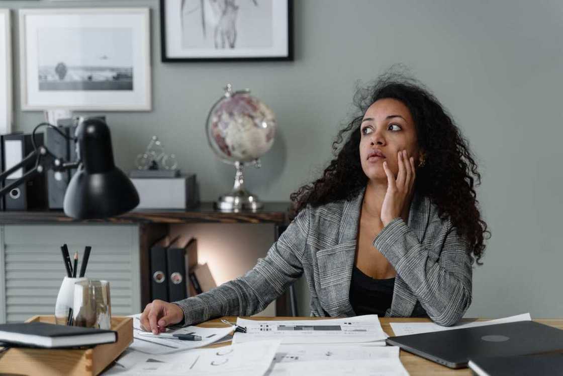 A woman in plaid blazer sitting with her hand on her face