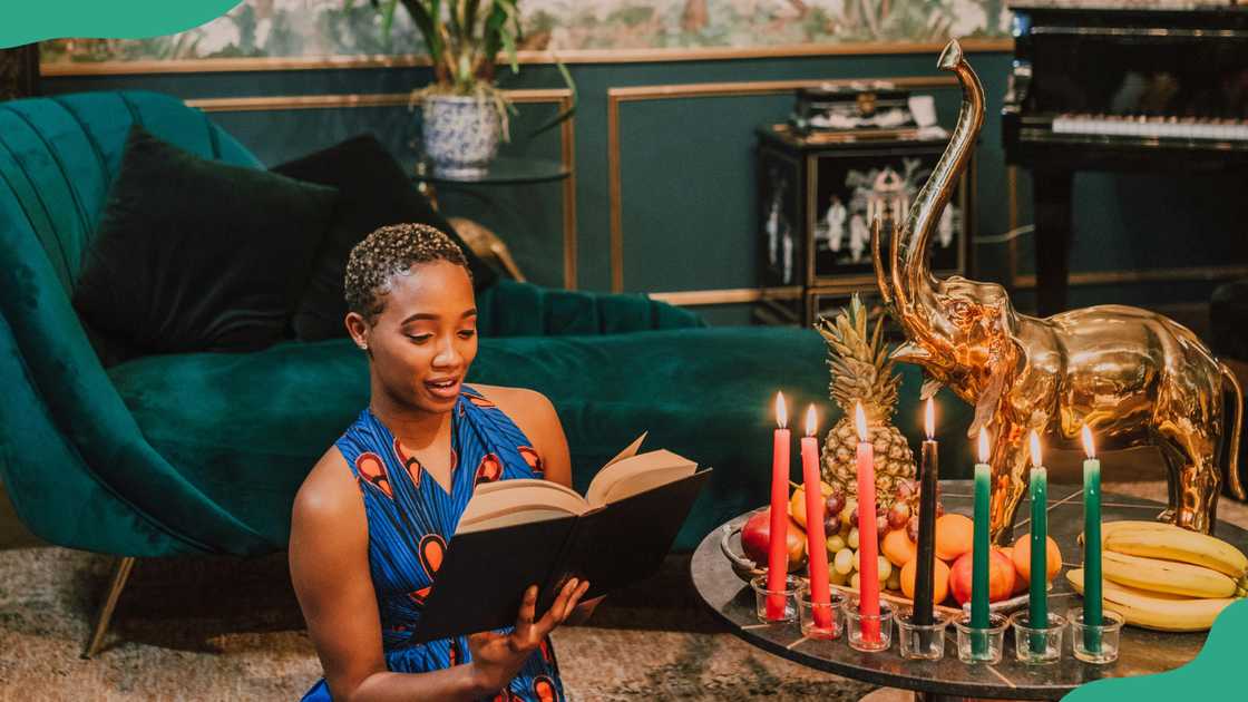 A woman in a blue dress reads a book beside a table
